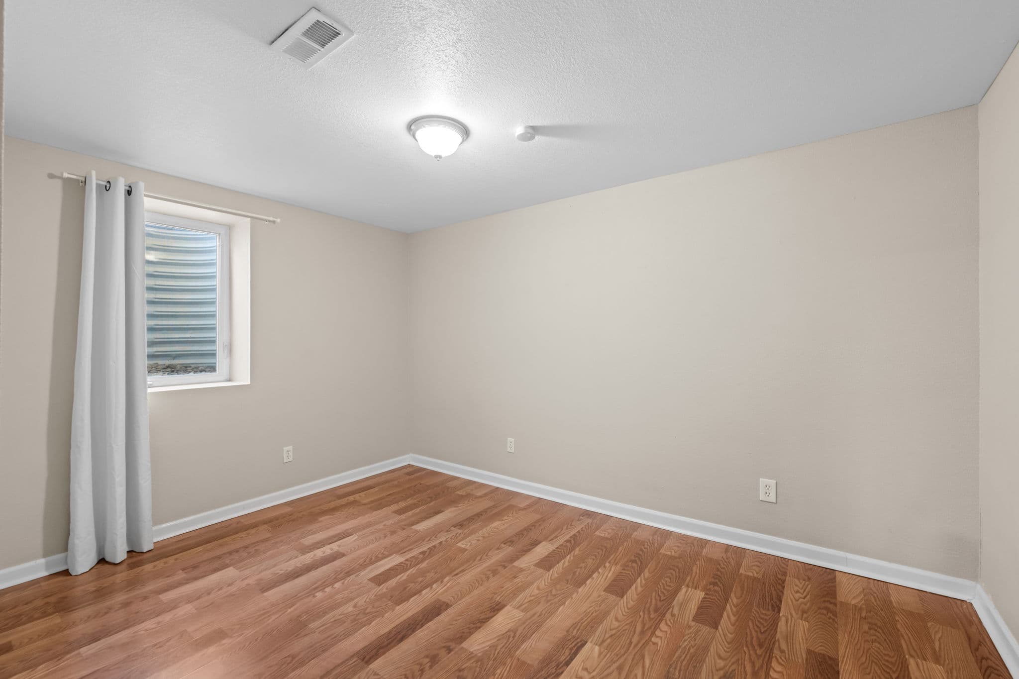 A lower-level bedroom with a garden-level window