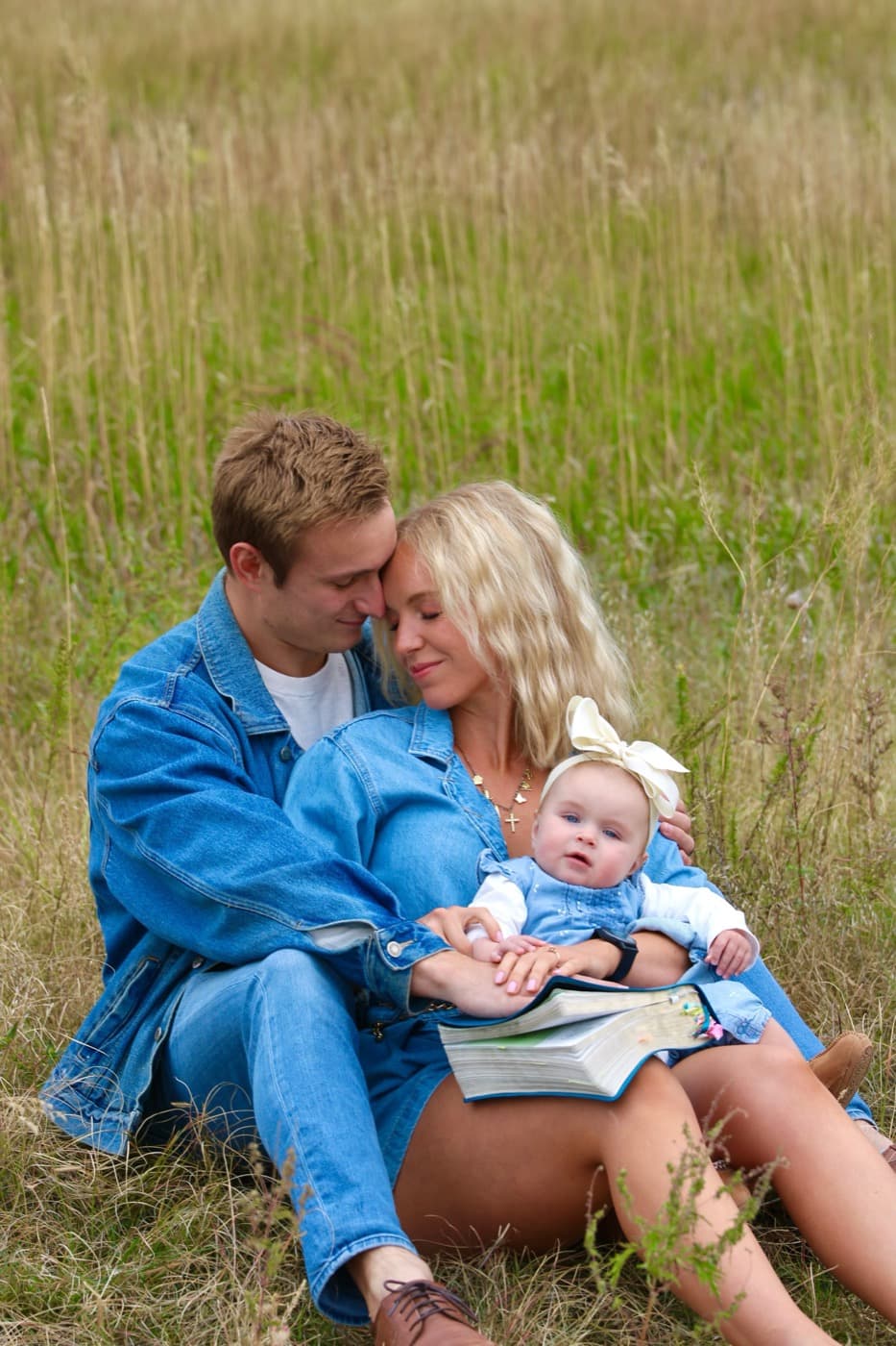 The Vaughan family sitting together in a field with their daughter